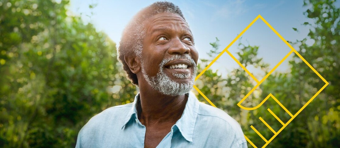 Uomo con la barba sorridente di fronte agli alberi con un contorno dell’immagine grafica Creare valore per gli azionisti