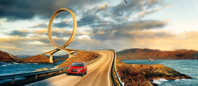 Red car driving on the road by the river