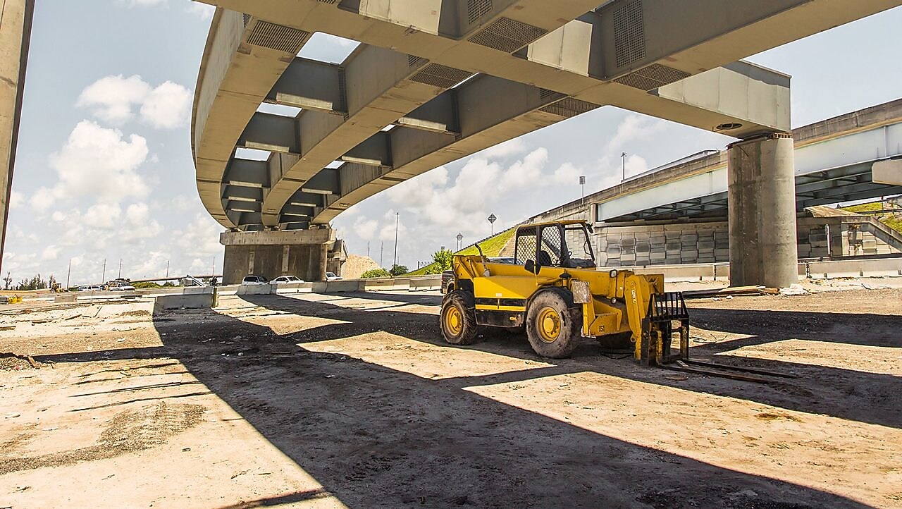 una scavatrice sotto un cavalcavia in costruzione