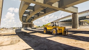 una scavatrice sotto un cavalcavia in costruzione