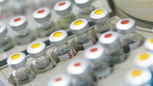 Fiale di medicine in fila posate su un contenitore, alcune con punti rossi sul coperchio, altre con punti gialli sul copercho