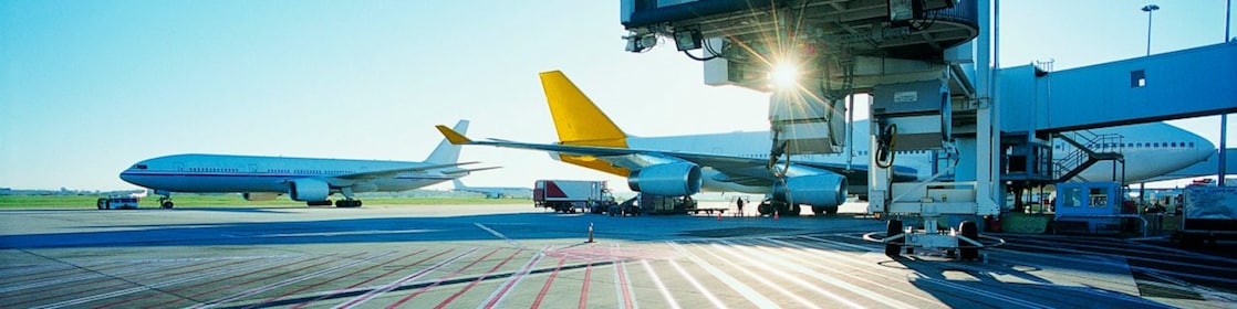 Vista di una pista di un aeroporto di primo mattino con il sole che sorge sopra due aeroplani