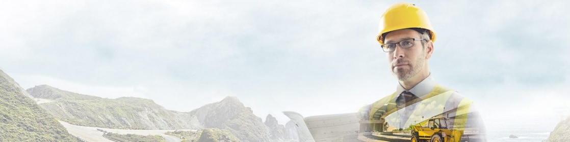 Un operaio con un casco giallo con sullo sfondo una strada di montagna
