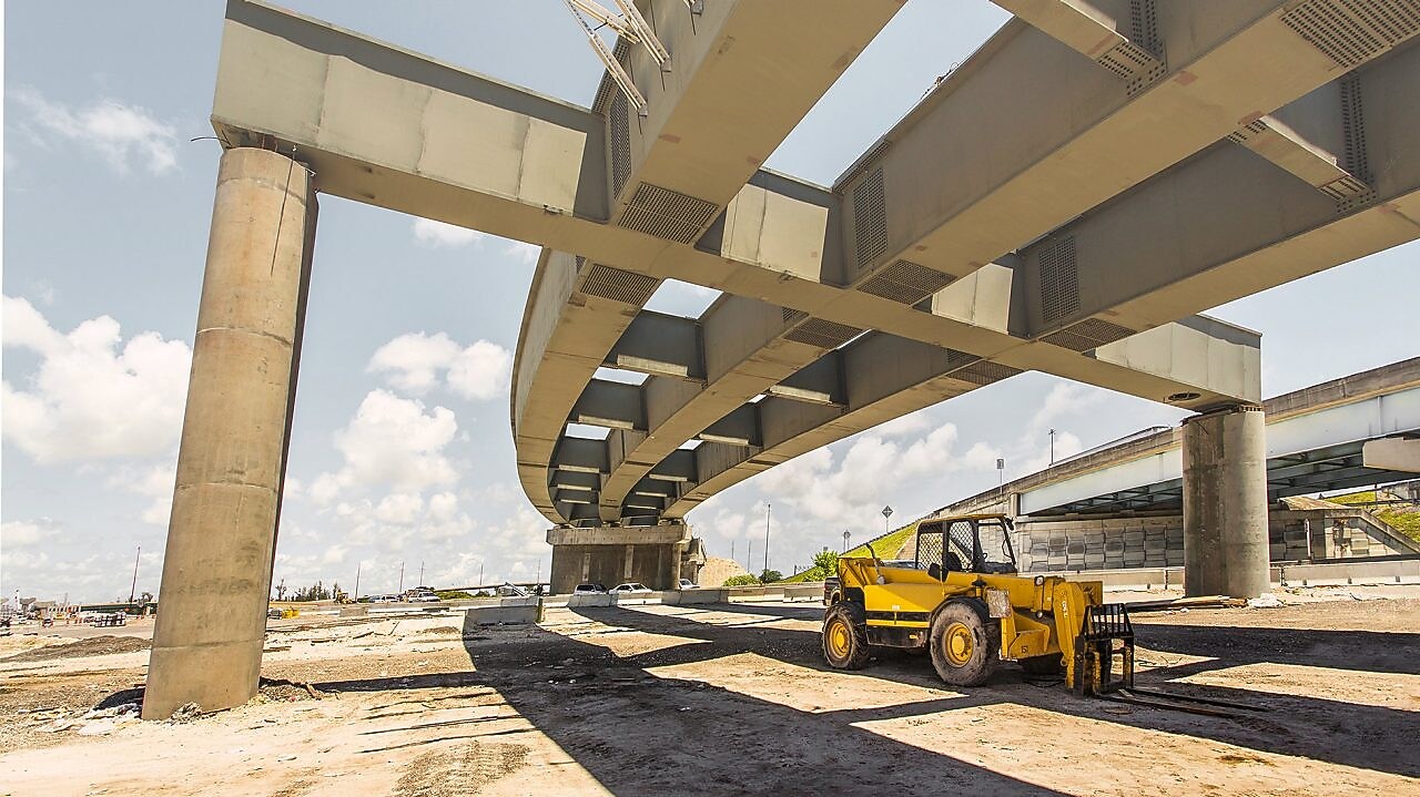 una scavatrice in un cantiere sotto un cavalcavia