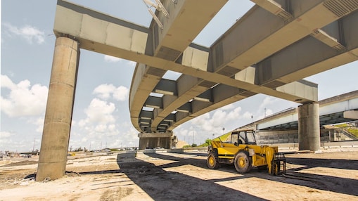 una scavatrice in un cantiere sotto un cavalcavia