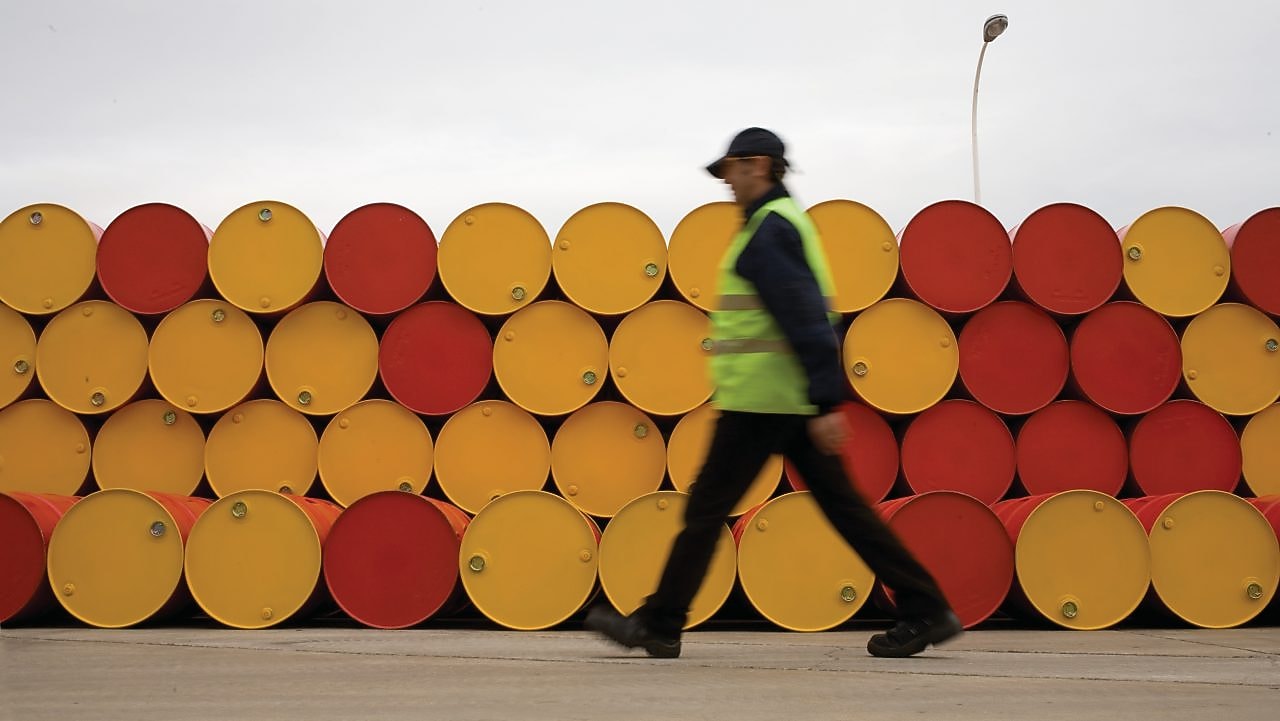 Un uomo che cammina accanto a fusti di lubrificanti