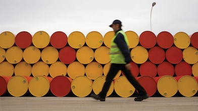 Un uomo che cammina accanto a fusti di lubrificanti