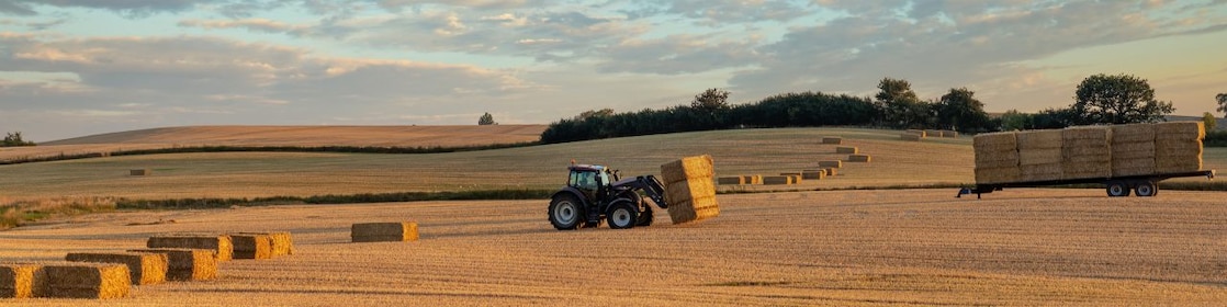 Agricoltore che raccoglie balle di fieno con un trattore nella sua fattoria