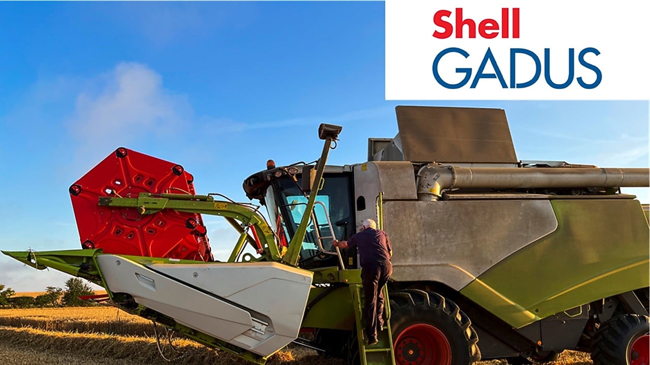 Una persona sta salendo i gradini di una grande mietitrebbia in un campo – grassi Shell Gadus