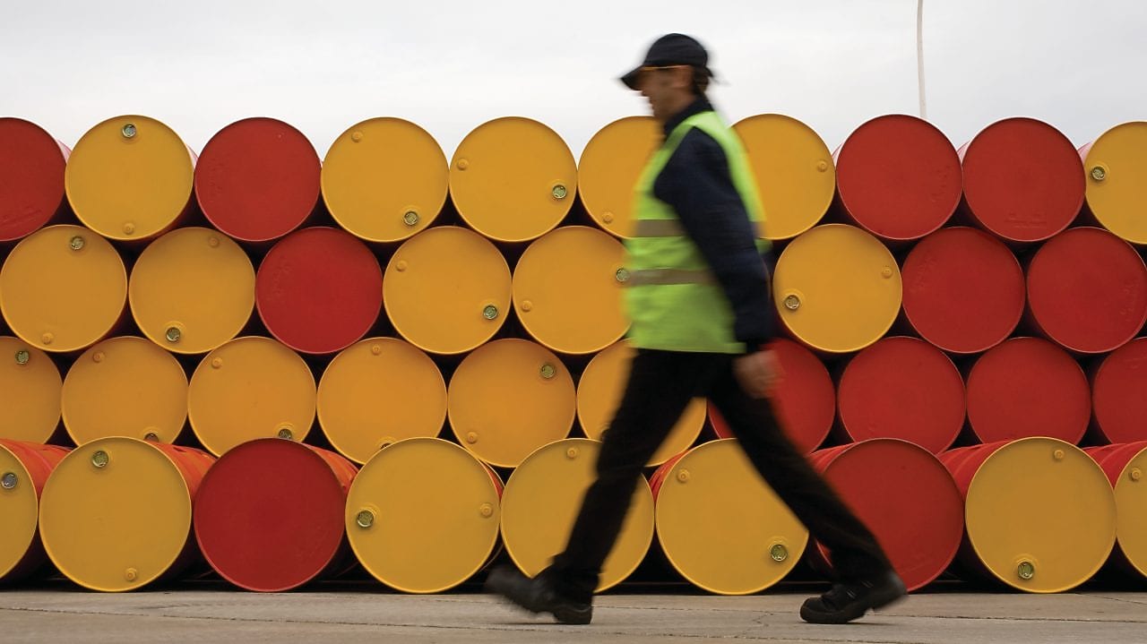 Un uomo che cammina accanto a fusti di lubrificanti