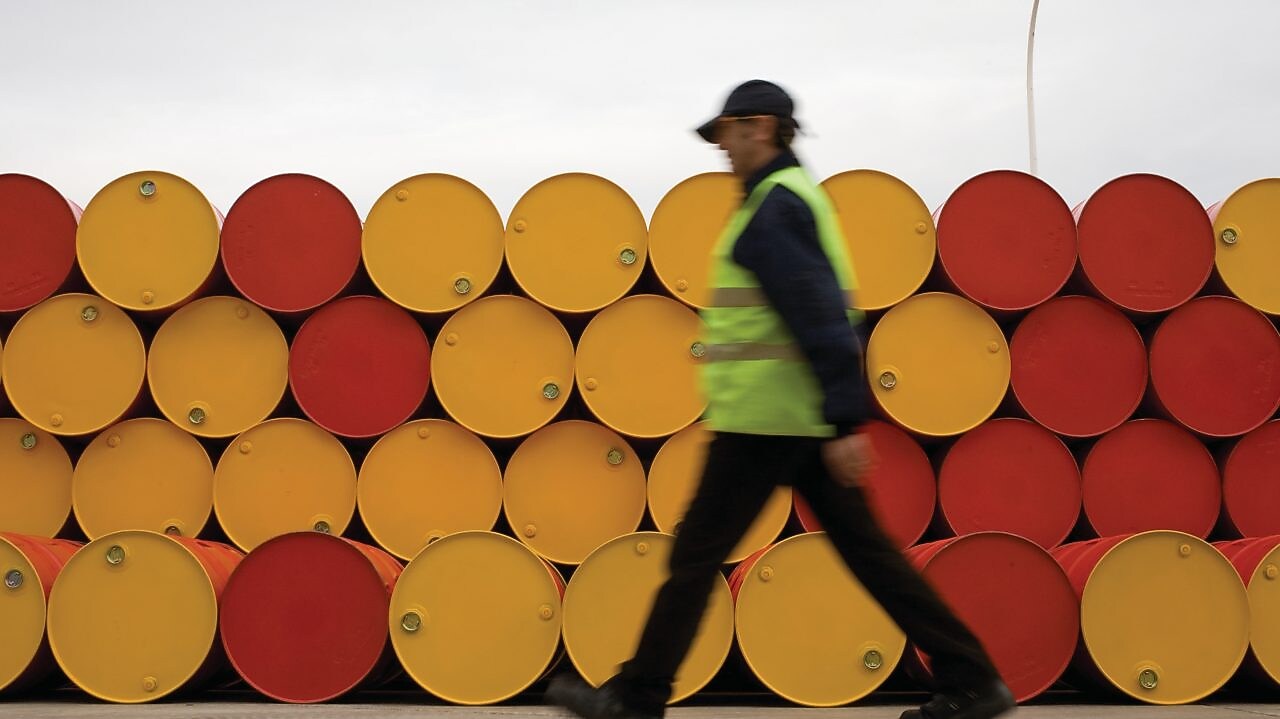 Un uomo che cammina accanto a fusti di lubrificanti