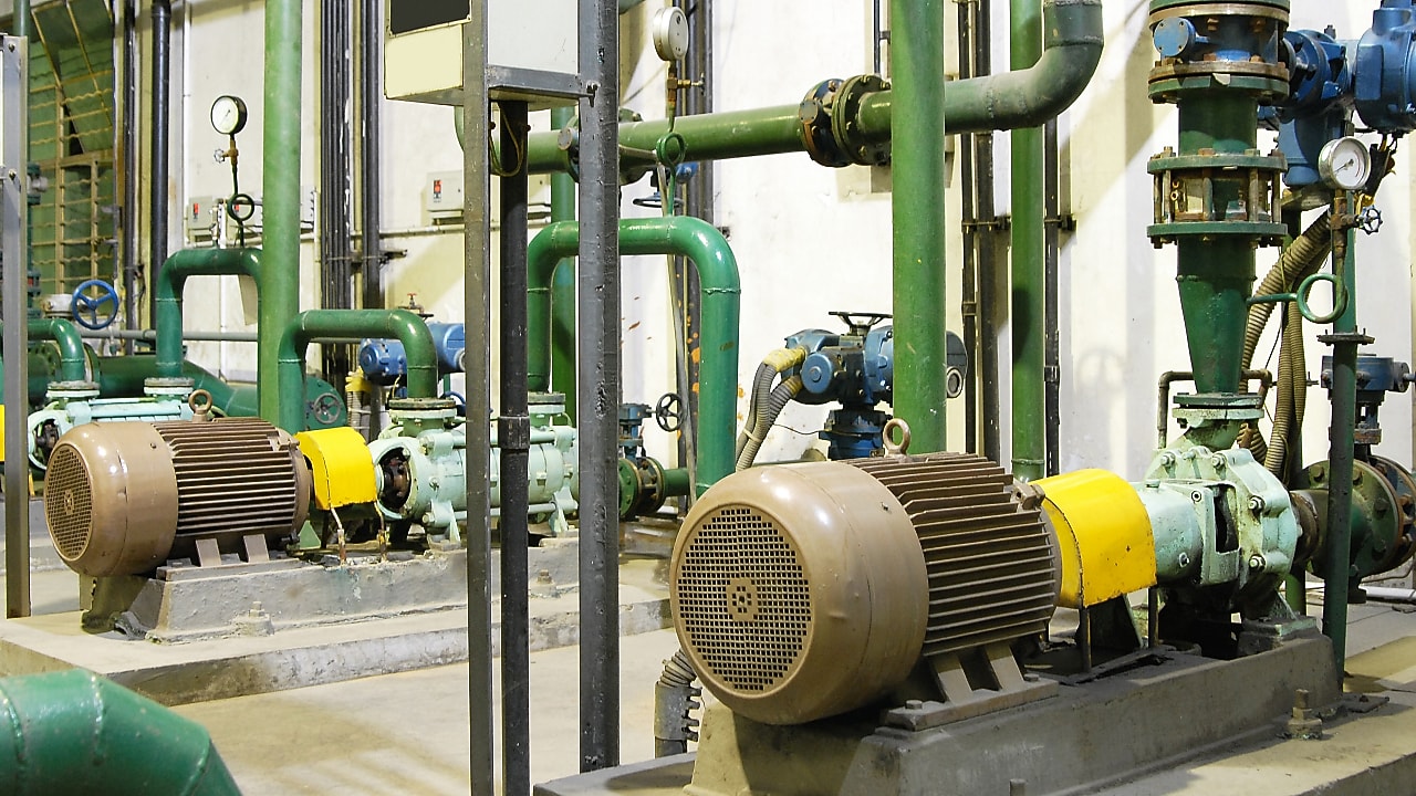 Sala motori a gas industriale con pompe, motori e tubazioni verdi per la produzione di energia.