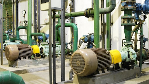 Sala motori a gas industriale con pompe, motori e tubazioni verdi per la produzione di energia.