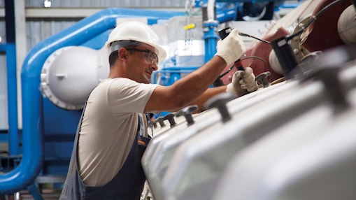 Tecnico che esegue manutenzione su un motore a gas stazionario in un impianto di produzione energetica.