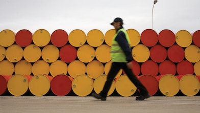 Un uomo che cammina accanto a fusti di lubrificanti