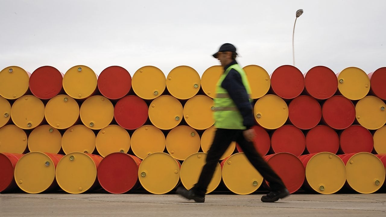 Un uomo che cammina accanto a fusti di lubrificanti