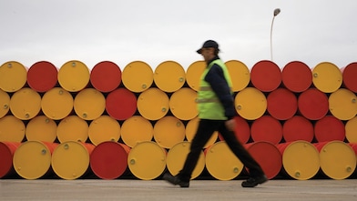 Un uomo che cammina accanto a fusti di lubrificanti