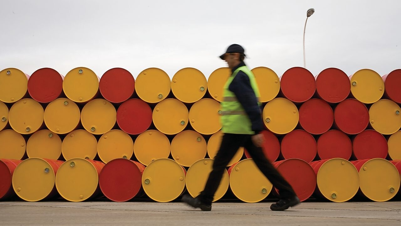 Un uomo che cammina accanto a fusti di lubrificanti