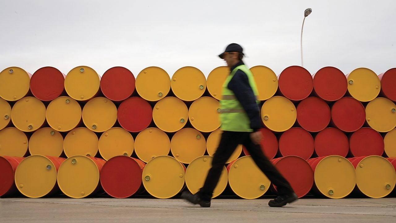 Un uomo che cammina accanto a fusti di lubrificanti