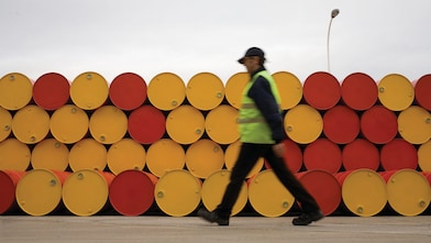 Un uomo che cammina accanto a fusti di lubrificanti