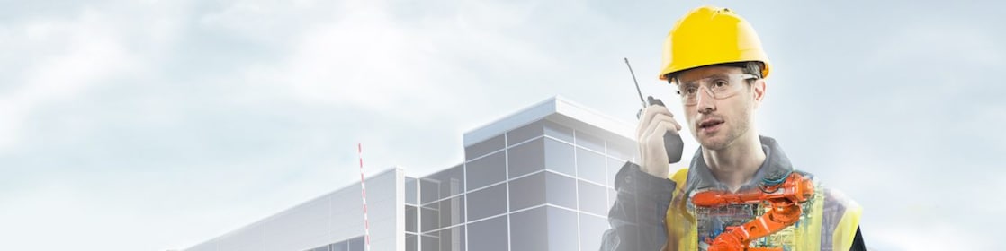 un uomo con un casco giallo che parla in una radio con sullo sfondo con un grande edificio