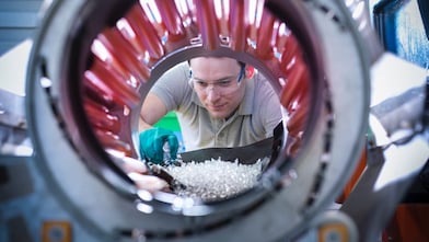Uomo che versa pellet di plastica in una molazza mescolatrice