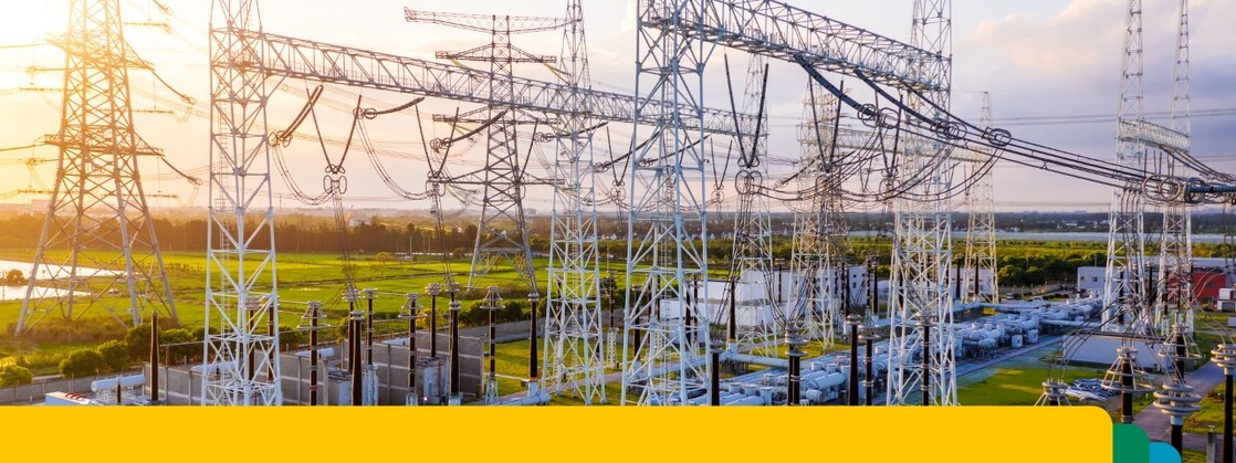 Electrical power substation with interconnected high-voltage transmission lines and equipment at sunset.