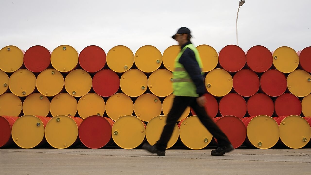 Un uomo che cammina accanto a fusti di lubrificanti