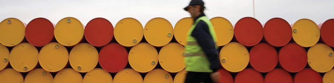 Un uomo che cammina accanto a fusti di lubrificanti