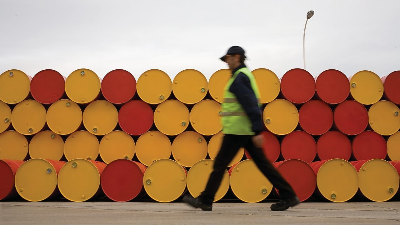 Un uomo che cammina accanto a fusti di lubrificanti