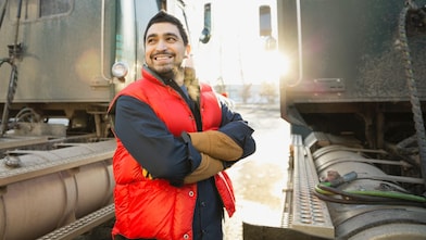 Confident worker standing by semi-trucks outdoors