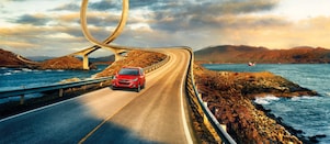 Red car driving on the road by the river