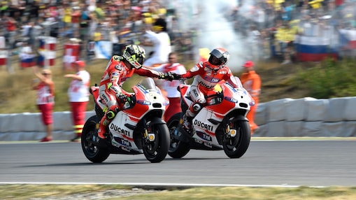 Two bikers shaking hands as they ride