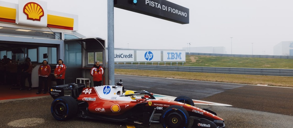 Shell scientists and Scuderia Ferrari HP drivers conversing in the Shell Trackside Laboratory at a Grand Prix circuit