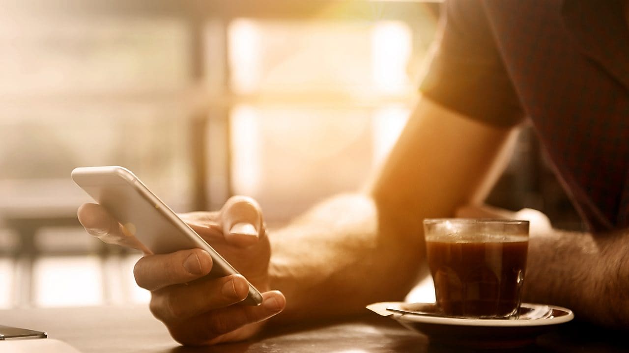 Man having a coffee looking at his smartphone